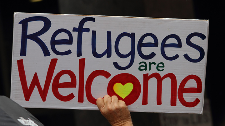 Hand holding sign saying Refugees are Welcome