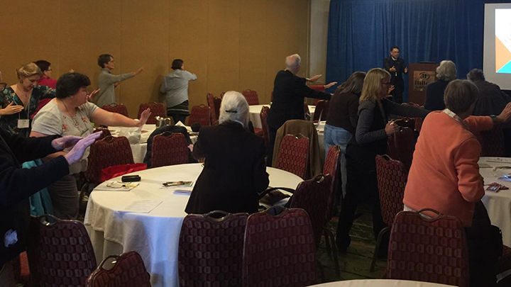 Group of people standing around tables gesturing in the air